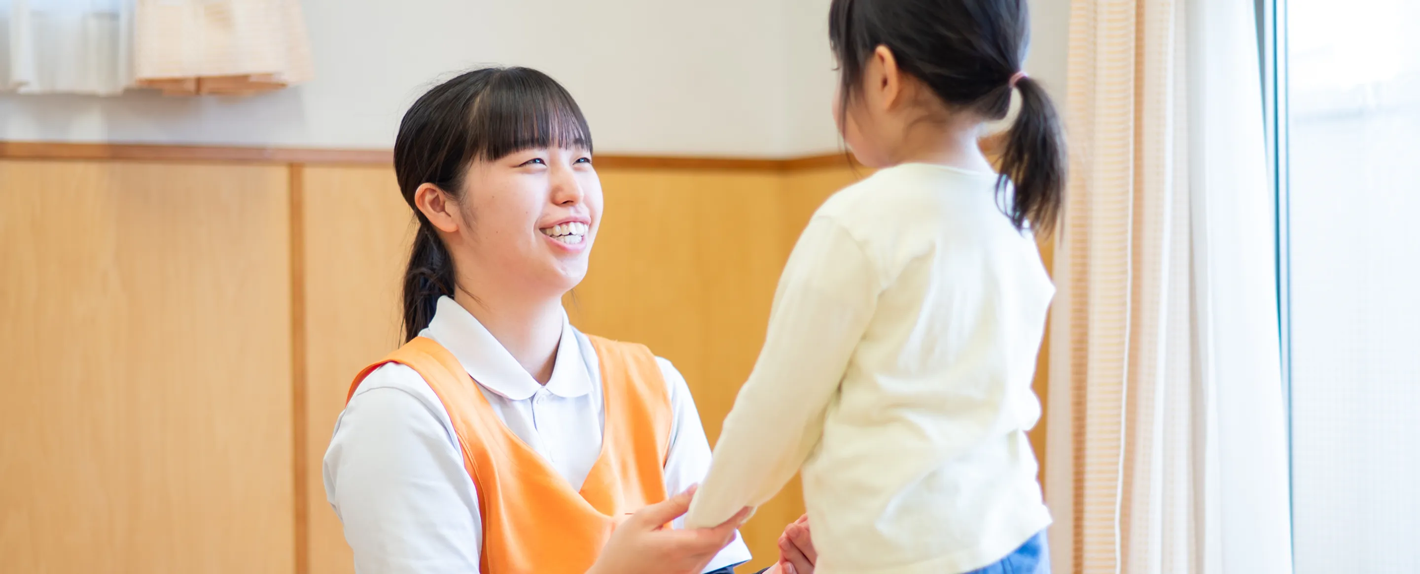 子どもと笑顔で向き合う保育士の女性