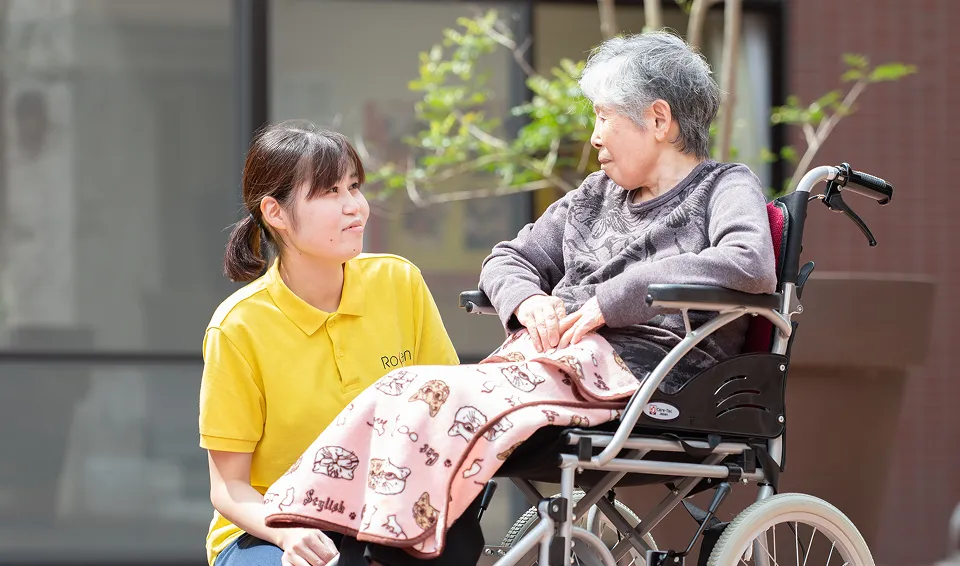 車椅子に座るご利用者と笑顔で会話する介護職員