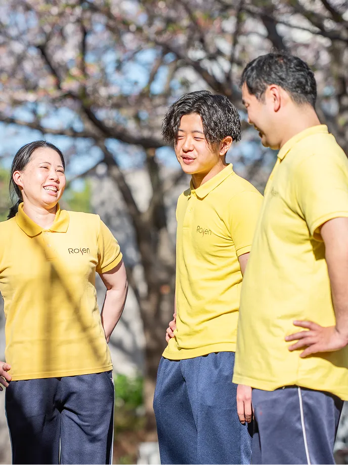 桜の木の前で談笑する3人の職員