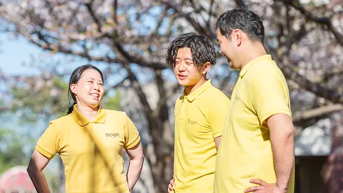 桜の木の前で談笑する3人の職員