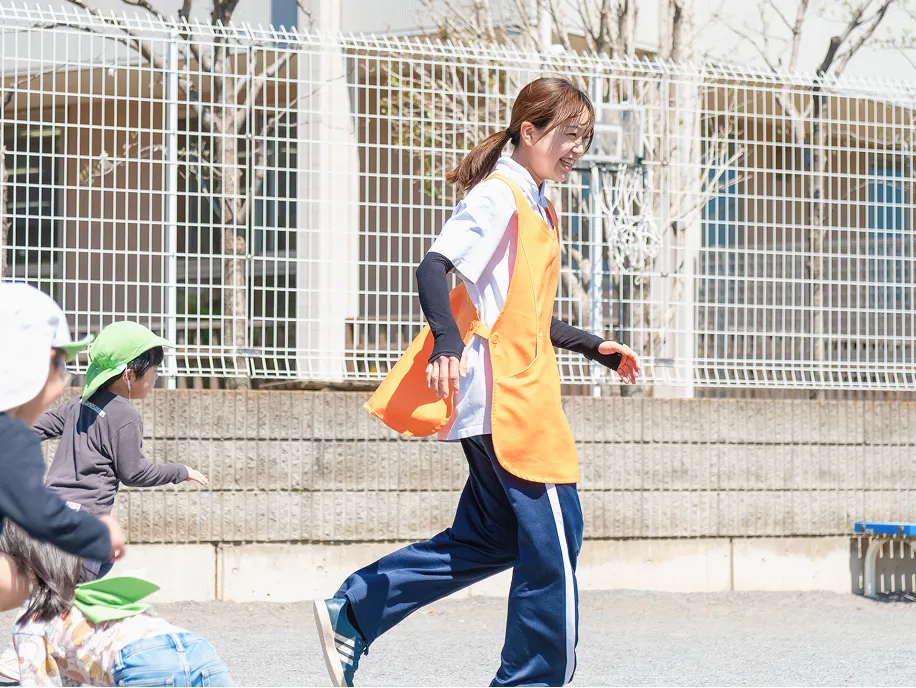 園庭で走って遊ぶ子どもたちと保育士