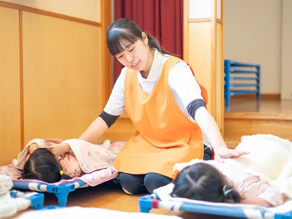 保育士の女性が子どもたちを寝かしつける様子